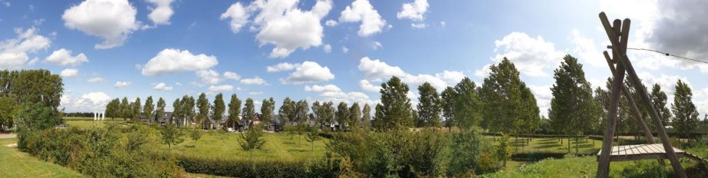 Panoramafoto met groene bomen en goed belichte schapenwolken